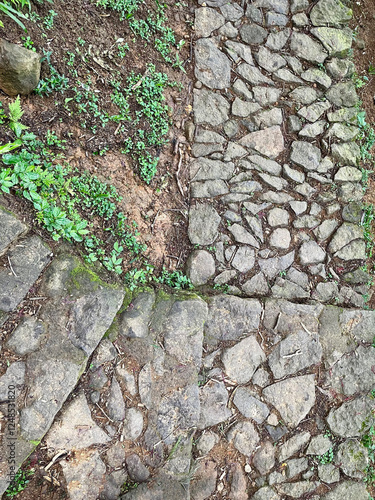 Winding path on the edge of a cliff, a hiking trail in the forest with stacked rocks on the path