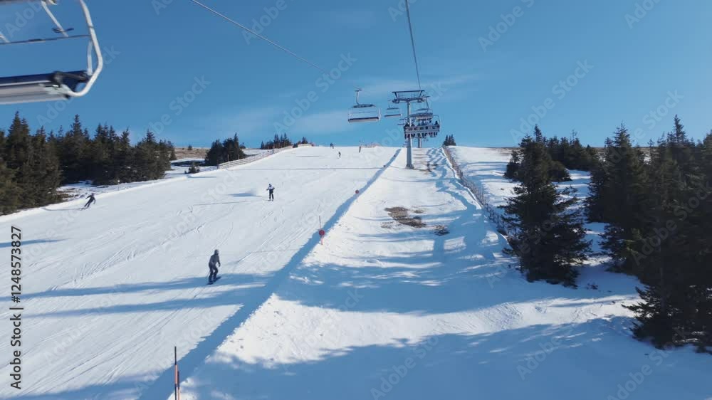 Experience the thrill of skiing on a bright, sunny day as skiers glide down the snowy slopes while chairlifts transport adventurers to the top. (4K) Experience the thrill of skiing on a bright, sunny day as skiers glide down the snowy slopes while chairlifts transport adventurers to the top. (4K)