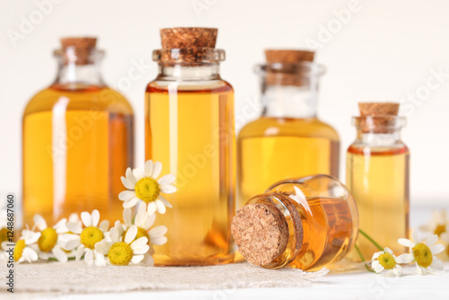 Wallpaper Mural Bottles of essential oil and chamomile flowers on white wooden table, closeup Torontodigital.ca