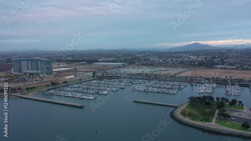 Aerial drone orbit around Chula Vista marina during an overcast evening, wide shot with city of Chula Visa in the background. photo