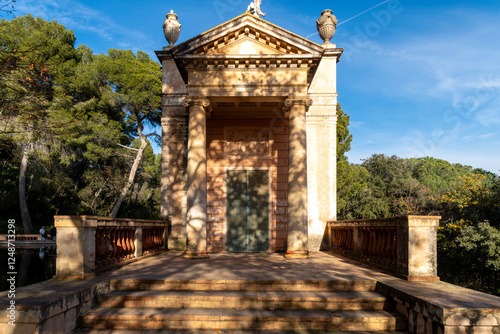 A garden pathway with a small fountain, leading towards symmetrical hedges and an elegant formal landscape. photo