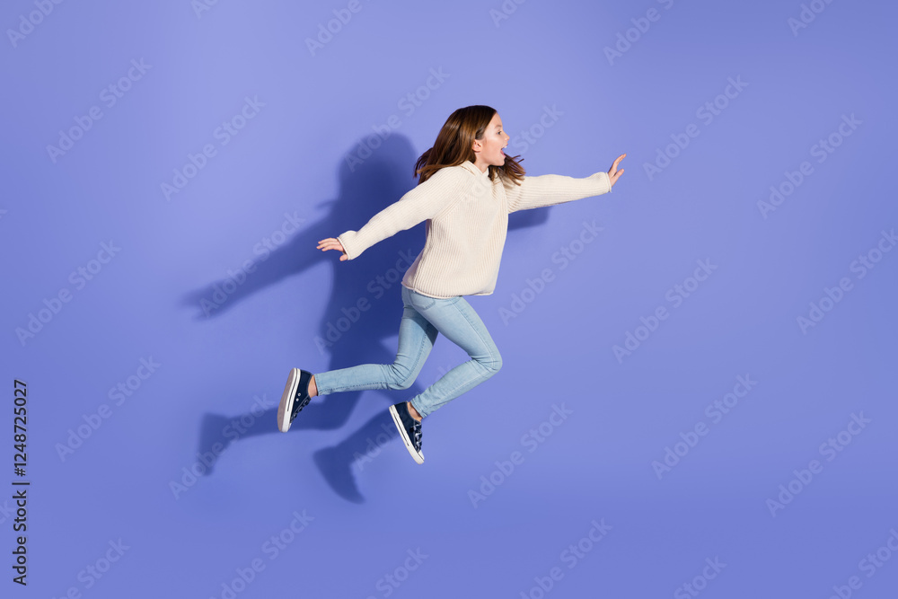 Energetic young girl jumping against a purple background wearing a white sweater and light jeans. Energetic young girl jumping against a purple background wearing a white sweater and light jeans.