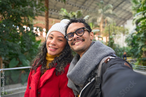 Happy tourist couple taking selfie in atocha station tropical garden