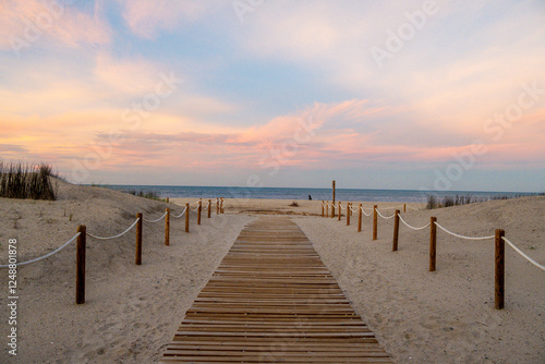 Wooden boardwalk leading to sandy beach at sunset