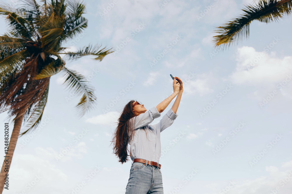 Palm trees and clear blue sky captured by a woman with her cell phone, creating a tropical and serene atmosphere, with tall palm trees prominently featured in the background Palm trees and clear blue sky captured by a woman with her cell phone, creating a tropical and serene atmosphere, with tall palm trees prominently featured in the background