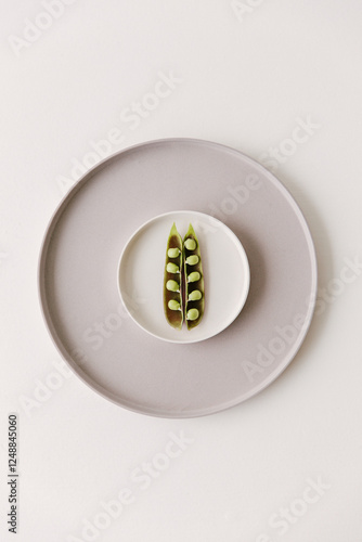 Marrow fat peas still in their skin lying on a small plate.