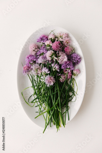 A bunch of flowering chives gathered on a oval shaped dish.