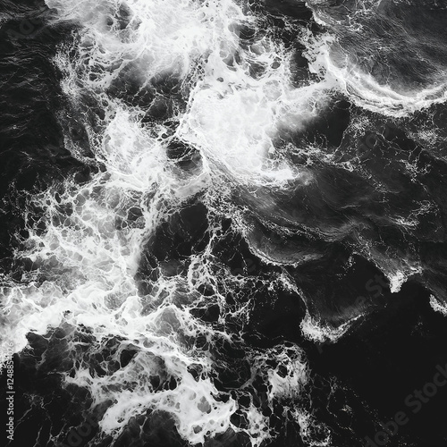 Black and white photograph of ocean waves. Aerial view, dark shore, crashing waves, deep black sea. Top view, abstract background.