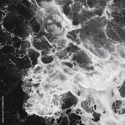Black and white photograph of ocean waves. Aerial view, dark shore, crashing waves, deep black sea. Top view, abstract background.