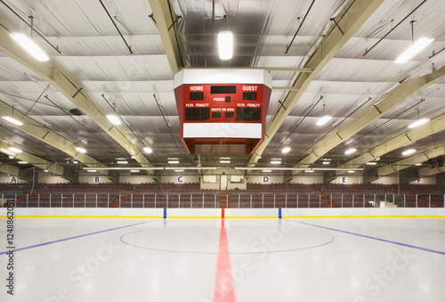 An indoor ice hockey arena, with an overhead electronic score board.