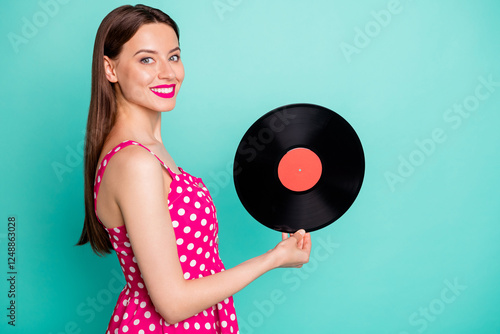 Portrait of lovely girl holding vinyl record disc smiling wearing dotted dresss skirt isolated over green teal turquoise background photo