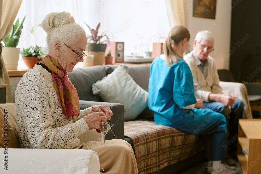 Side view of elegant senior woman wearing glasses while sitting in chair and crocheting Side view of elegant senior woman wearing glasses while sitting in chair and crocheting