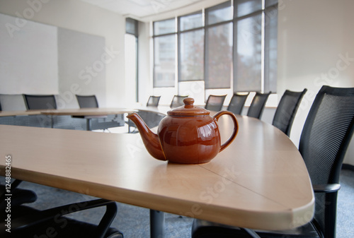 A brown china teapot on boardroom table in empty boardroom.