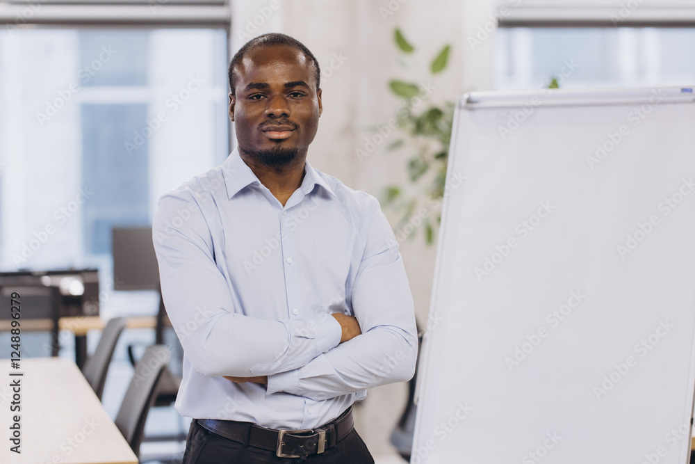 Fototapeta premium Professional african american businesswoman standing near blank flipchart, preparing for strategic presentation in sleek corporate workspace