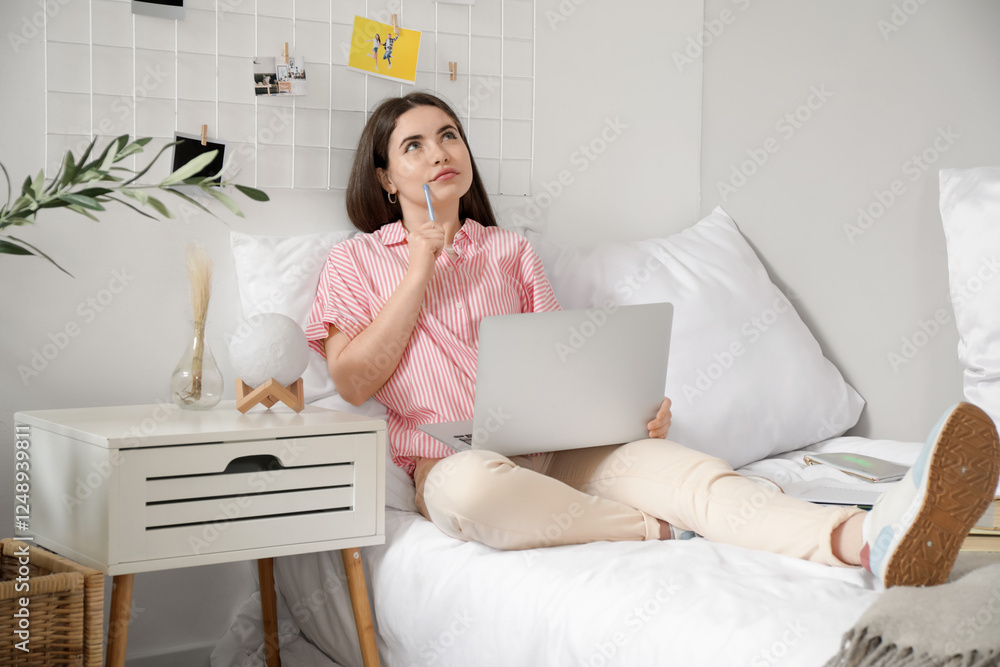 Thoughtful female student studying with laptop on bed at home Thoughtful female student studying with laptop on bed at home
