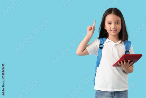 Cute little happy Asian girl with backpack and calculator pointing at somethi...