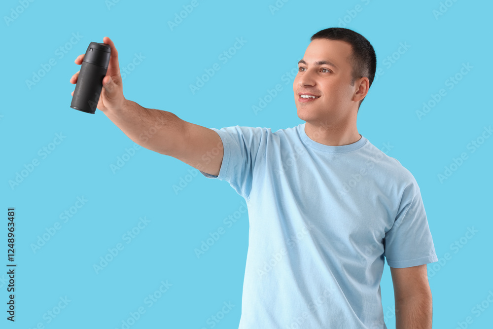 Fototapeta premium Handsome young man with deodorant on blue background
