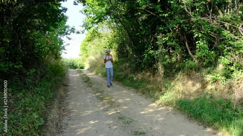 Wallpaper Mural Woman hiking through a countryside landscape, surrounded by open fields, fresh air, and peaceful rural scenery. She enjoys the natural beauty and serenity of the outdoors. Torontodigital.ca