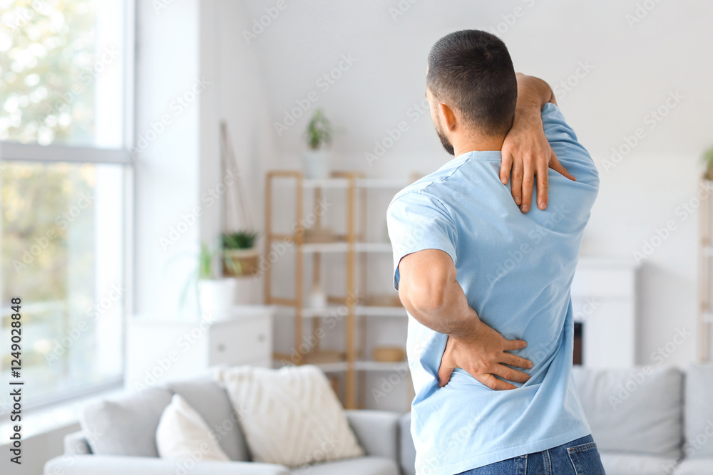 Young man suffering from back pain at home Young man suffering from back pain at home