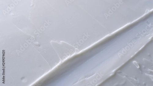 A spatula spreads a smooth, creamy skincare product on a surface, creating soft, elegant textures. The rich consistency and gentle motion evoke a sense of luxury, hydration, and self-care.
