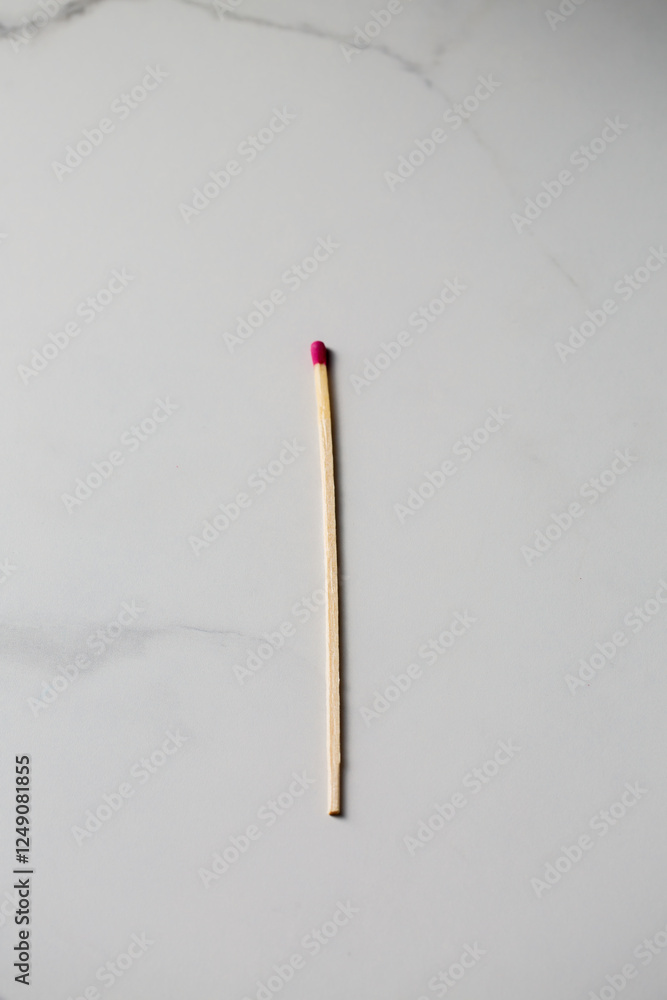 One long fireplace match with pink head on white marble background One long fireplace match with pink head on white marble background