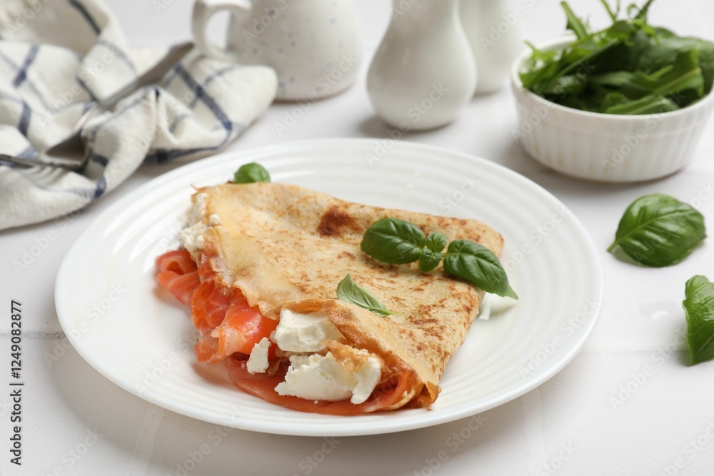 Delicious crepe with salmon, cream cheese and basil on white table, closeup Delicious crepe with salmon, cream cheese and basil on white table, closeup