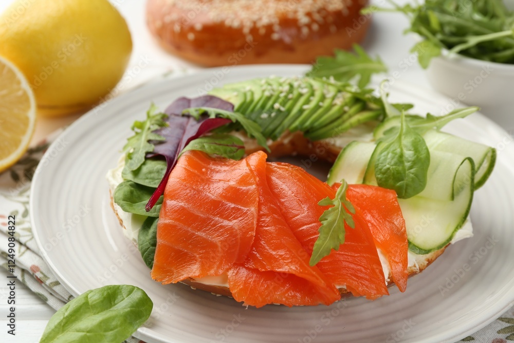 Delicious bagel with salmon, cream cheese, cucumber and avocado on white wooden table, closeup Delicious bagel with salmon, cream cheese, cucumber and avocado on white wooden table, closeup