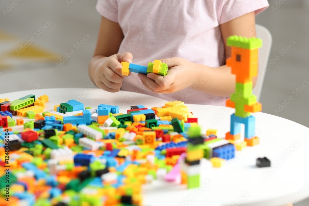 Girl playing with building blocks at white table indoors, closeup Girl playing with building blocks at white table indoors, closeup