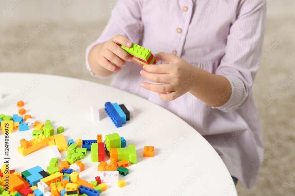 Girl playing with building blocks at white table indoors, closeup Girl playing with building blocks at white table indoors, closeup