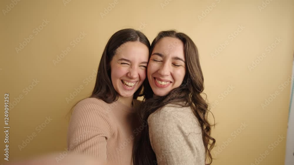Two young women embracing looking at camera, while take a selfie smiling Two young women embracing looking at camera, while take a selfie smiling
