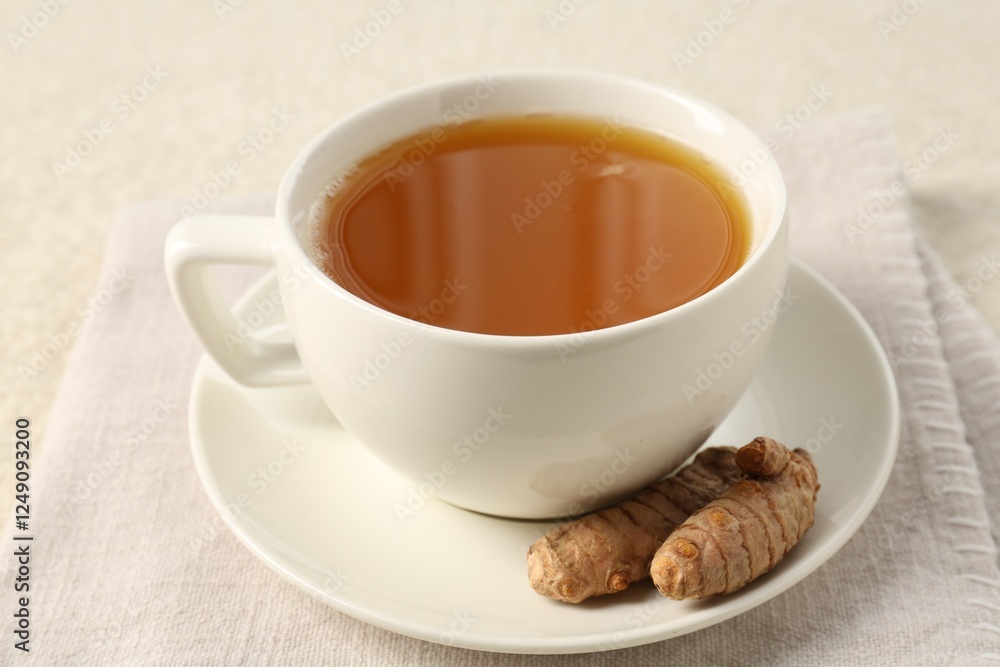 Fototapeta premium Aromatic turmeric tea and rhizomes on white textured table, closeup