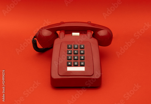 A vintage red push-button telephone on a matching red background. The classic design and bold color create a nostalgic and minimalist aesthetic, perfect for retro and vintage-themed compositions.