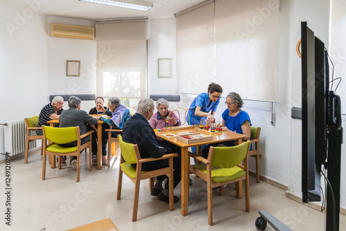Photography Nurse helping senior residents during board game activity in nursing home