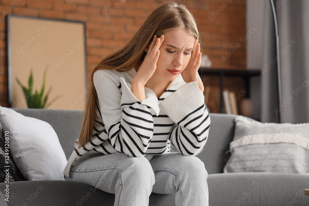Worried young woman sitting on sofa at home Worried young woman sitting on sofa at home