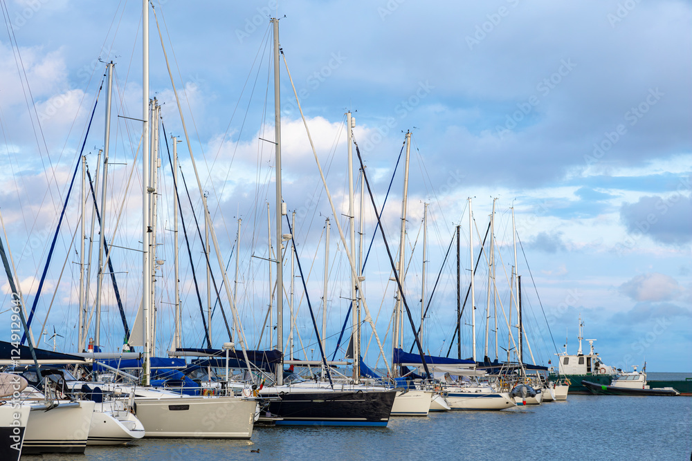 Obraz premium marina with a pier many yachts moored, cloudy sky with sunset in the background