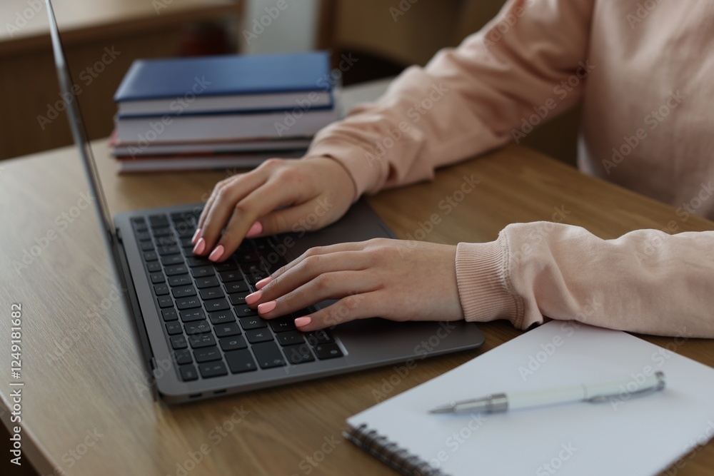 Girl using laptop at wooden desk in public library, closeup Girl using laptop at wooden desk in public library, closeup