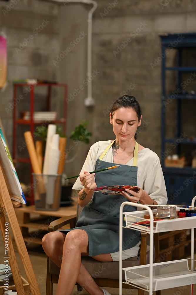 A focused artist sitting with a palette and brush, carefully mixing colors for her artwork, surrounded by studio tools and a calm, creative atmosphere A focused artist sitting with a palette and brush, carefully mixing colors for her artwork, surrounded by studio tools and a calm, creative atmosphere
