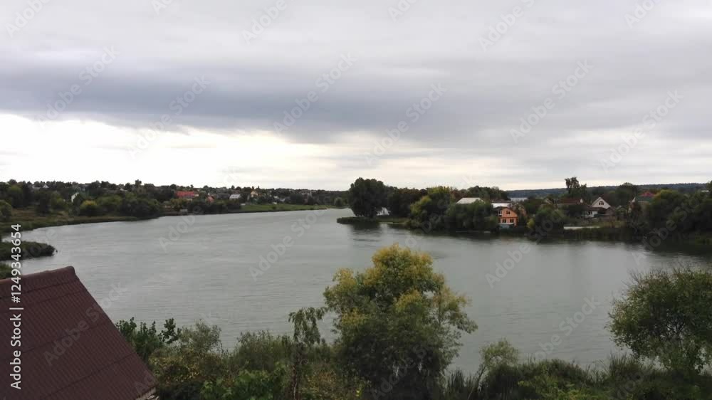 River with a few houses on the banks. The water is calm and the sky is cloudy River with a few houses on the banks. The water is calm and the sky is cloudy