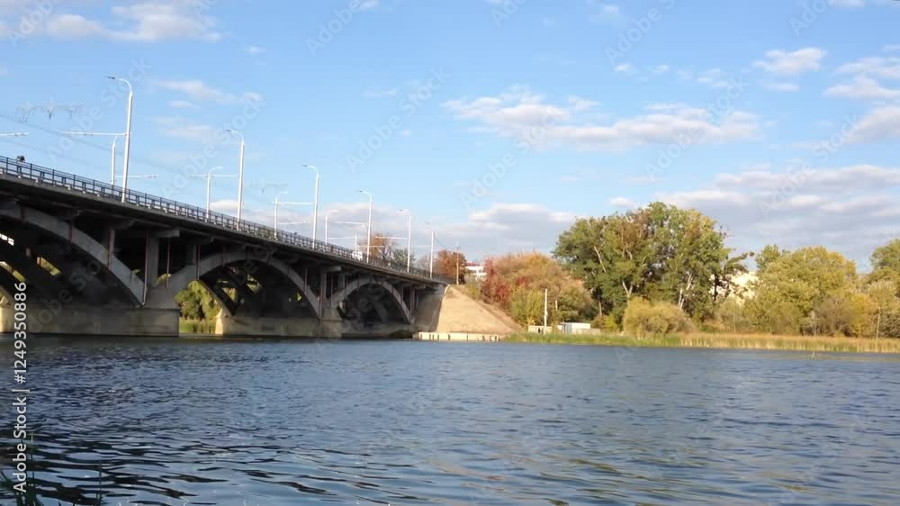 Bridge spans a river with a clear blue sky above. The bridge is a large structure with a few trees in the background Bridge spans a river with a clear blue sky above. The bridge is a large structure with a few trees in the background