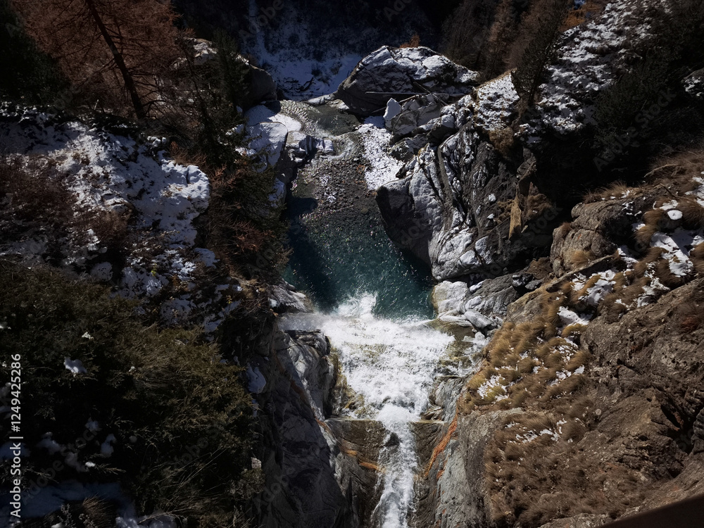 Obraz premium Stunning aerial view of lillaz waterfall cascading into a vibrant turquoise pool, surrounded by snow dusted rocks and trees in the aosta valley, italy Lillaz