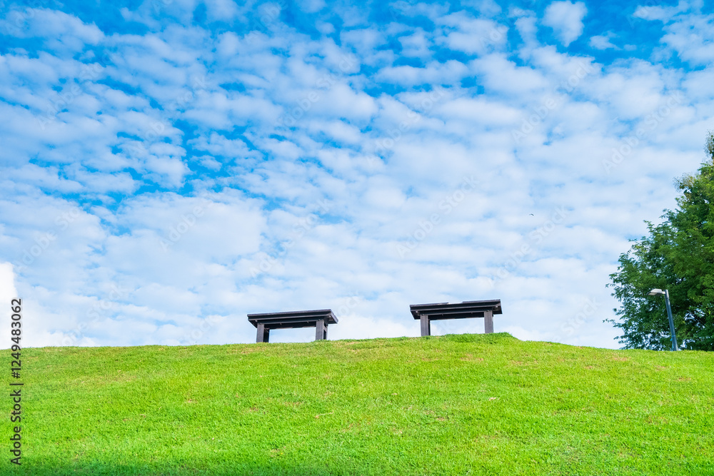 Garden bench with Green meadows with blue sky and clouds background, Landscape view of green grass on slope Scenic panoramic view on a beautiful sunny day,japanese picture concept.