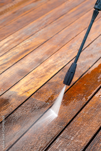 cleaning terrace with a power washer - high water pressure cleaner on wooden terrace surface