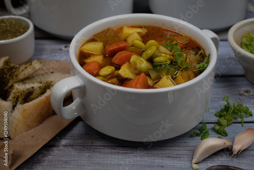 Potato, carrot and lima beans soup in white bowls on wooden backround, served with herb bread