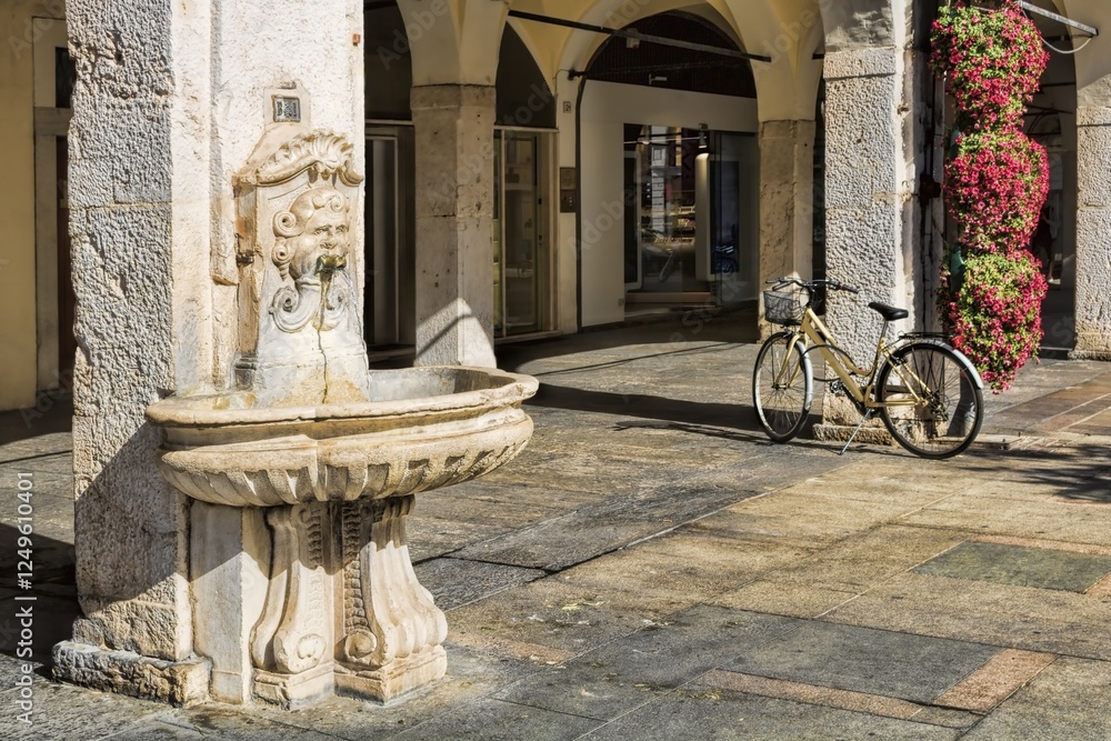 brescia, italien - arkaden mit altem brunnen und fahrrad