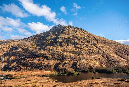 Landscape photography of mountain Beinn Maol Chaluim,  valley Glen Etive, Glencoe, Scotland, UK, winter condition, snow on the mountain peak, hiking, rocky hill, blue sky with clouds, travel photo