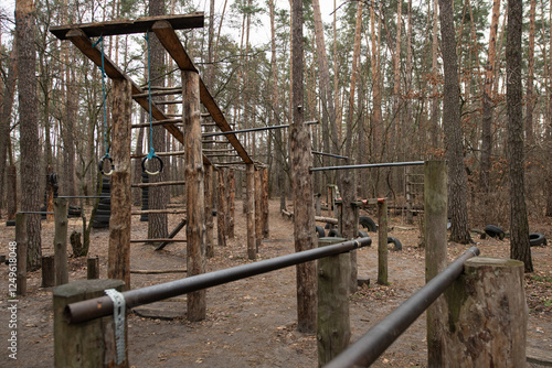 An outdoor sports ground set amidst trees offers various workout stations made of wood