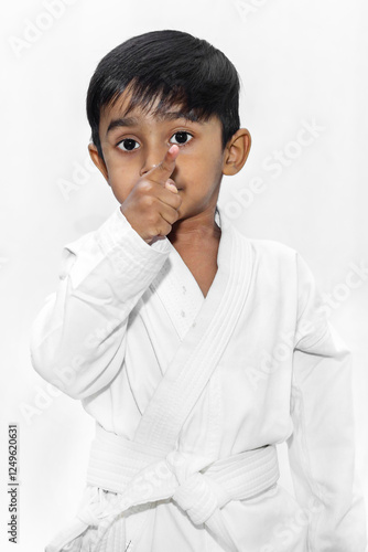 An Asian boy poses in a karate uniform. A boy in a white karate uniform and green belt demonstrating skills, practicing isolated on a white studio background. photo