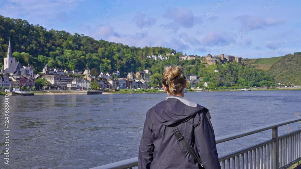 Following woman walking on a riverside pathway looking at beautiful view of the Rhine River Valley, Sankt Goar, Germany Following woman walking on a riverside pathway looking at beautiful view of the Rhine River Valley, Sankt Goar, Germany