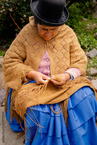 vertical adult aymara woman in pollera working on handcrafted wool textiles at home - work concept photo