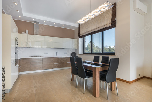 Elegant kitchen with a Roman curtain on the window in a private house. Stylish furniture, original lamps. photo